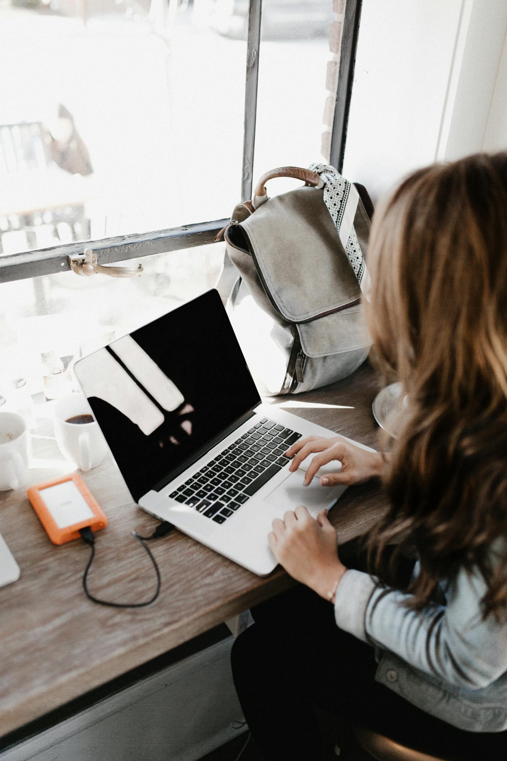 Close-up of a woman sitting at a table while using a Macbook